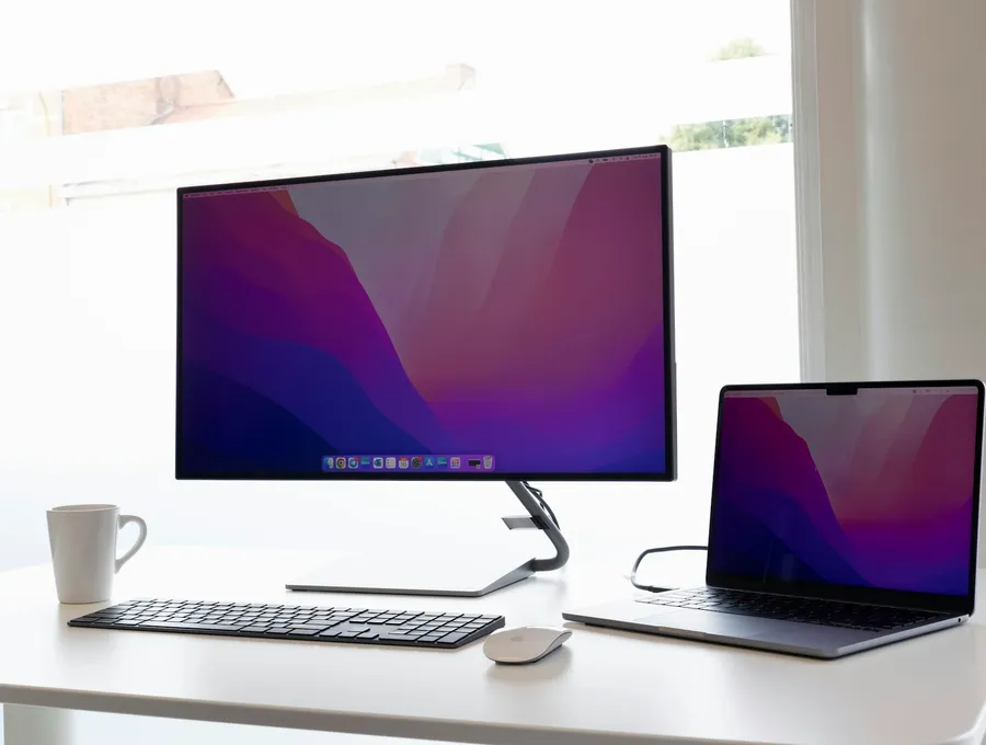Monitor und Notebook auf einem weißen Schreibtisch